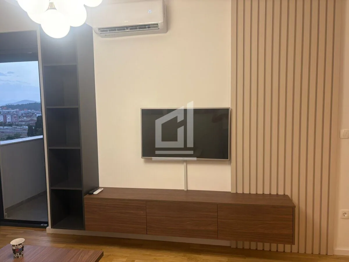 Dnevni boravak sa TV komodom i zidnim panelima.