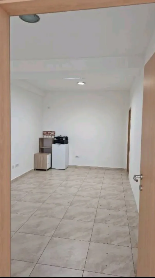 Empty room with ceramic floor tiles, viewed through a doorway.