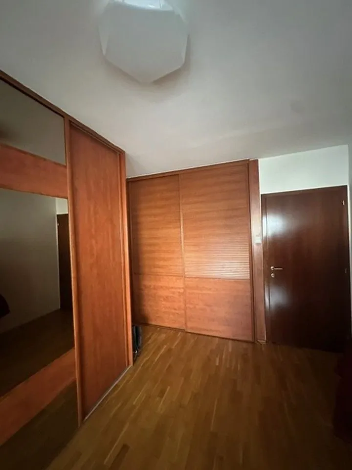 Spavaća soba sa ugradnim ormarima i drvenim podom.