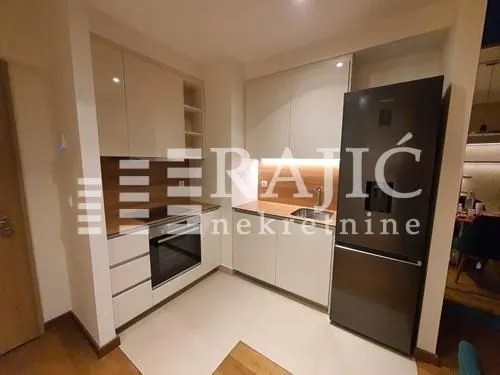 Modern kitchen with white cabinetry, built-in appliances, and a dark refrigerator.