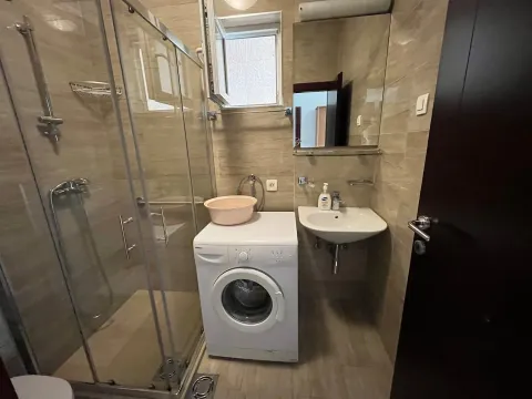 Small bathroom with a shower cabin, washbasin, and washing machine. - image 4
