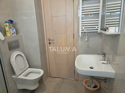 Small bathroom with a toilet, washbasin, and a light wood-toned door. - image 5