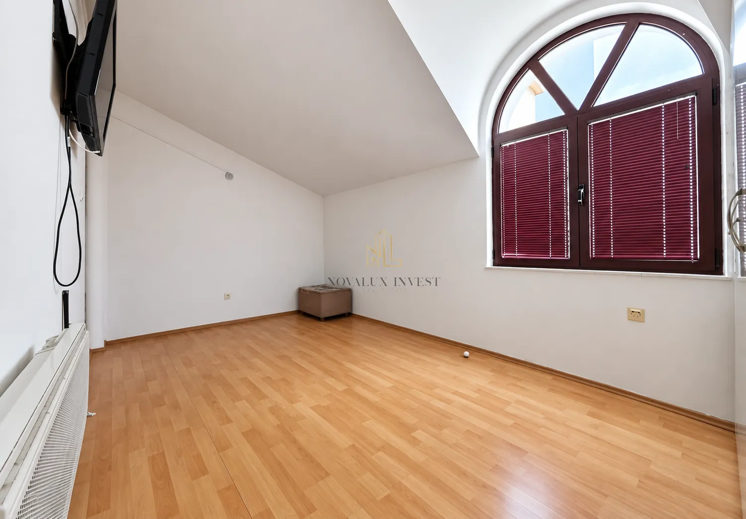 Empty room with laminate flooring, white walls, and a large arched window.