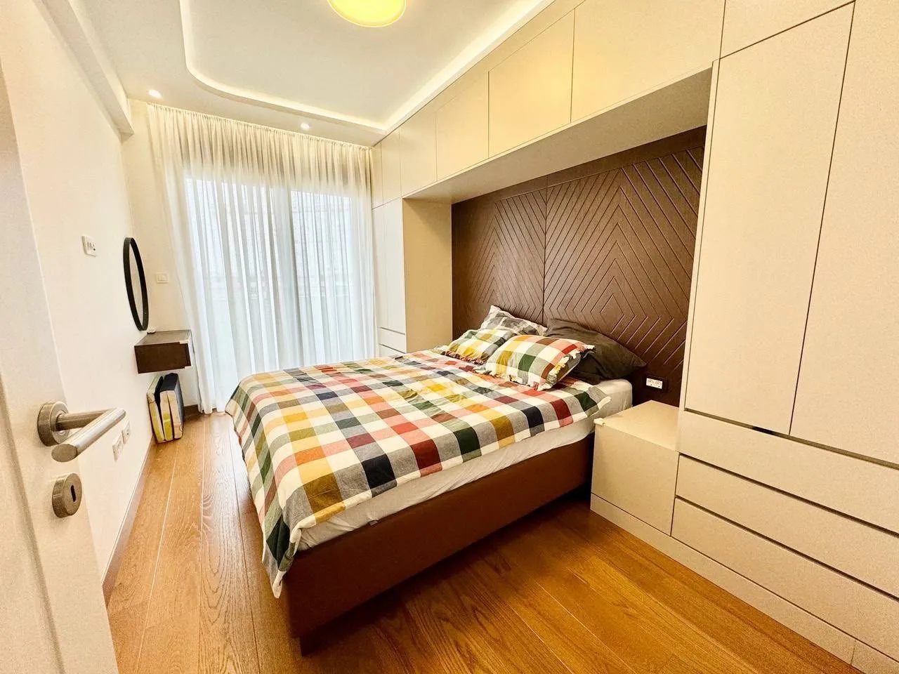 Svijetla spavaća soba sa ugradnim plakarima i modernim krevetom.