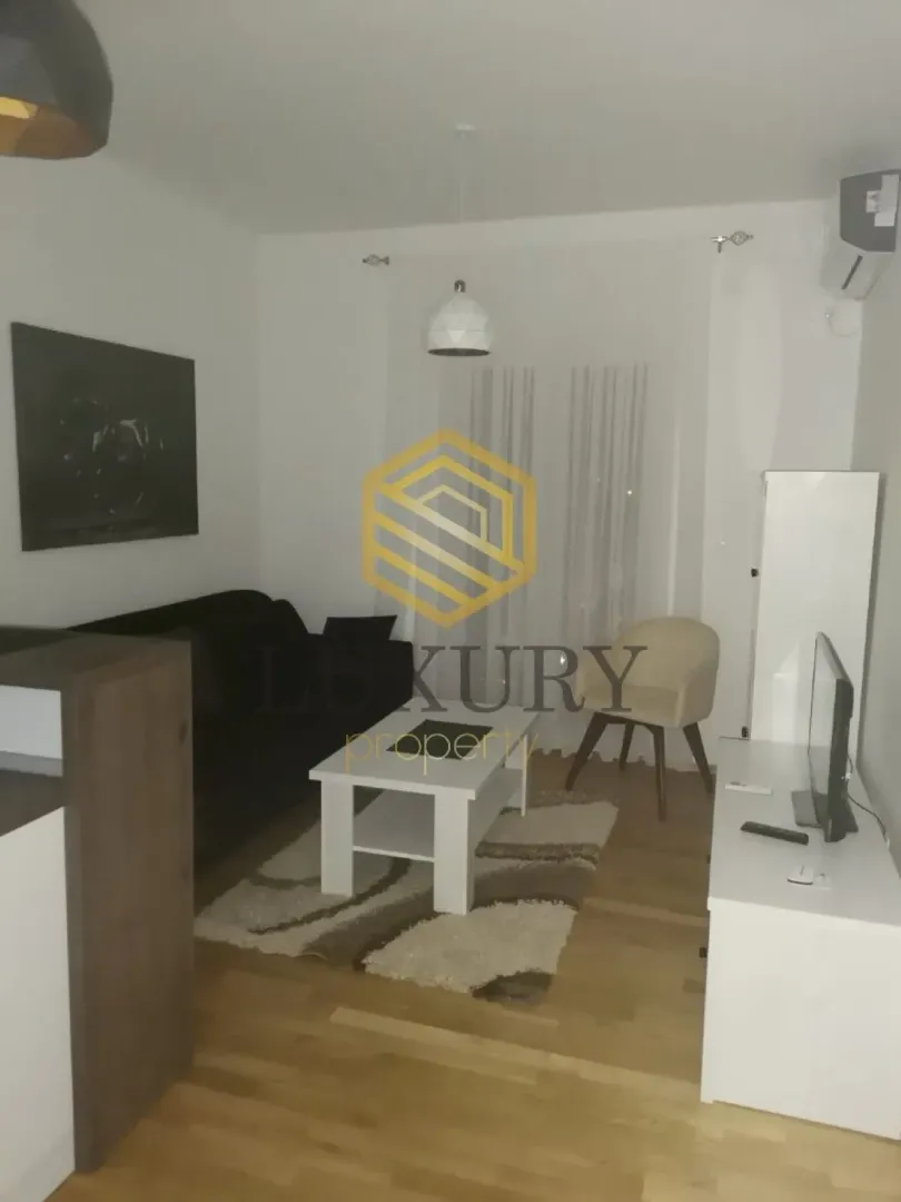 Dnevna soba opremljena garniturom, stočićem i televizorom.