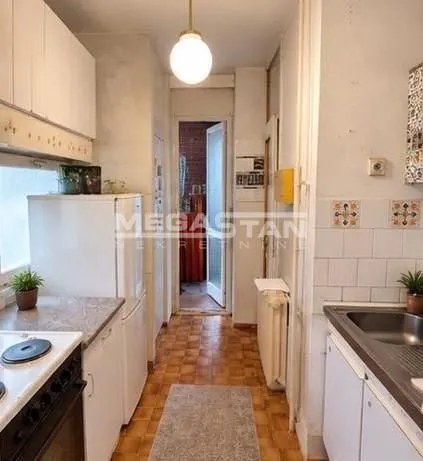 Narrow kitchen with white cabinetry and white goods.