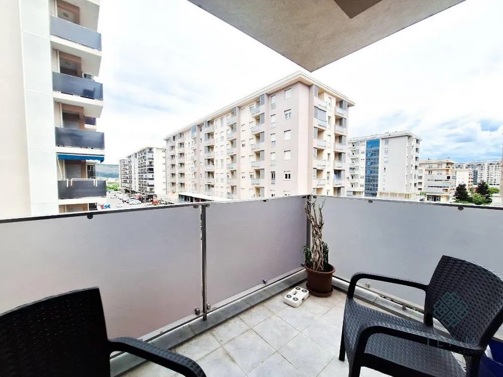 Small furnished balcony with a view of surrounding buildings and the city neighborhood.