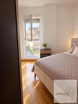 Spavaća soba sa bračnim krevetom, noćnim stočićem i prozorom koji gleda na naselje. - image 8