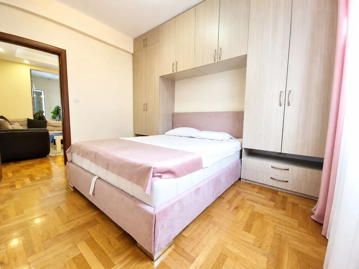 Namještena spavaća soba sa bračnim krevetom i ugradnim plakarima.