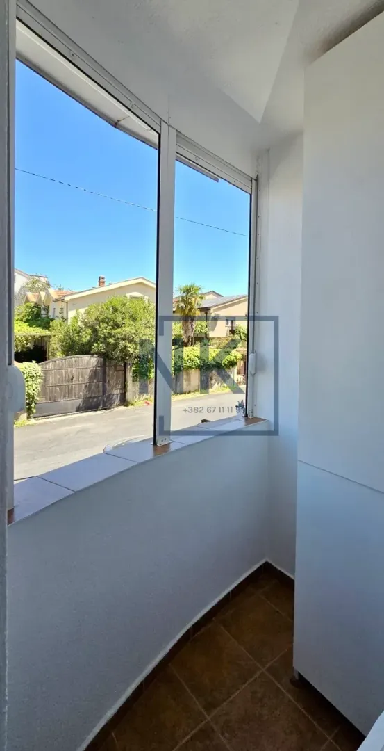 Glazed balcony with a view of the street and surrounding houses.