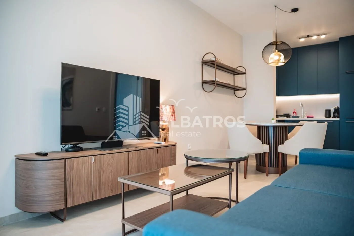 Living room with a TV, sofa, and a view of the dining area and kitchen.