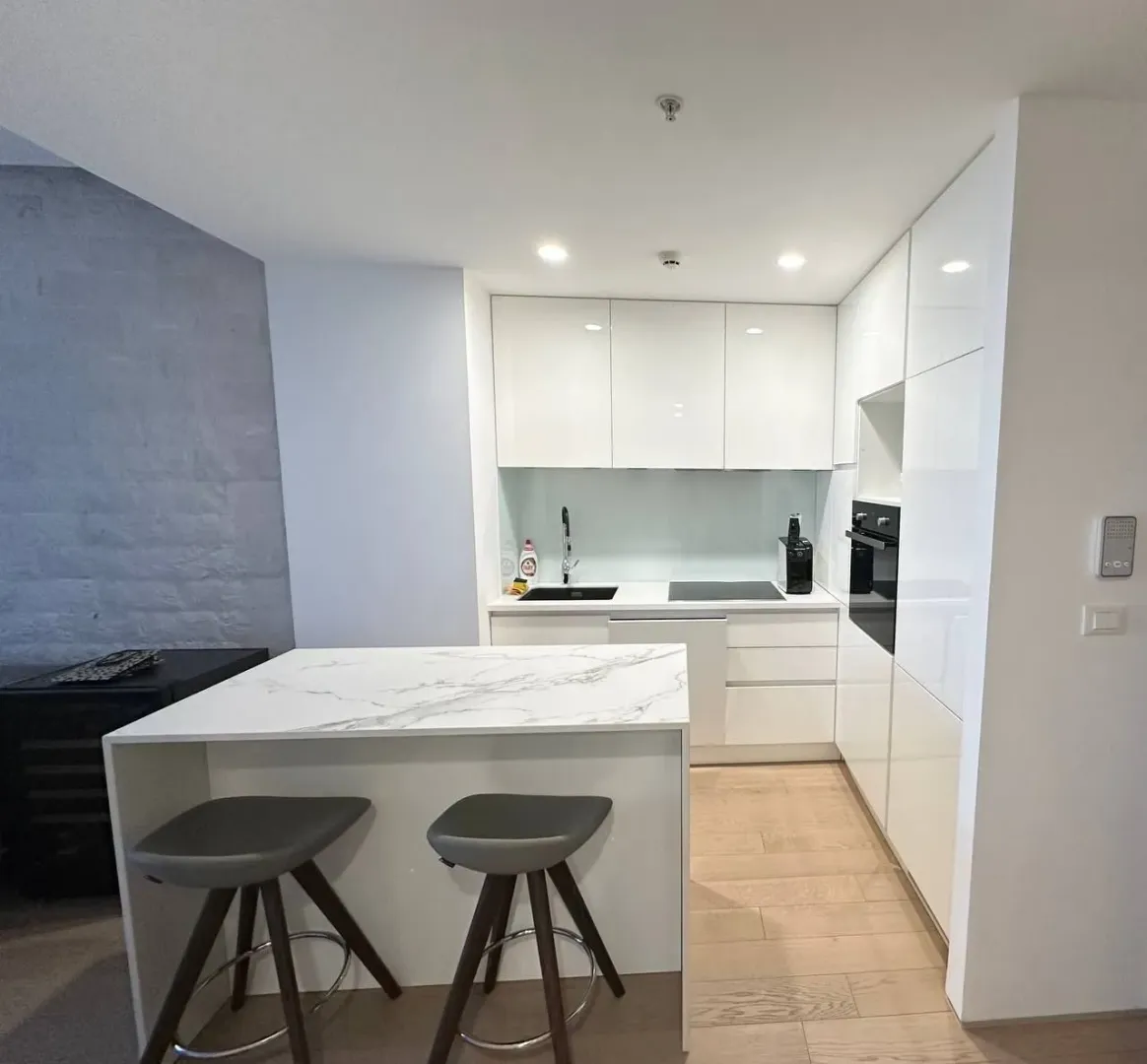 Modern white kitchen with an island and bar stools.