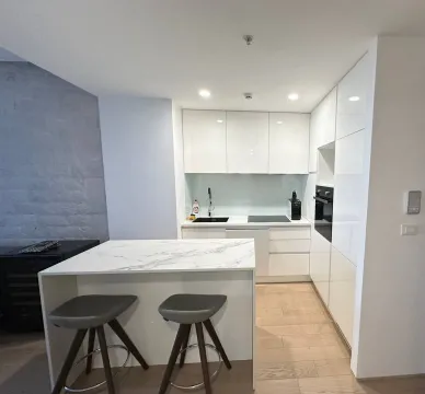 Modern white kitchen with an island and bar stools. - image 6