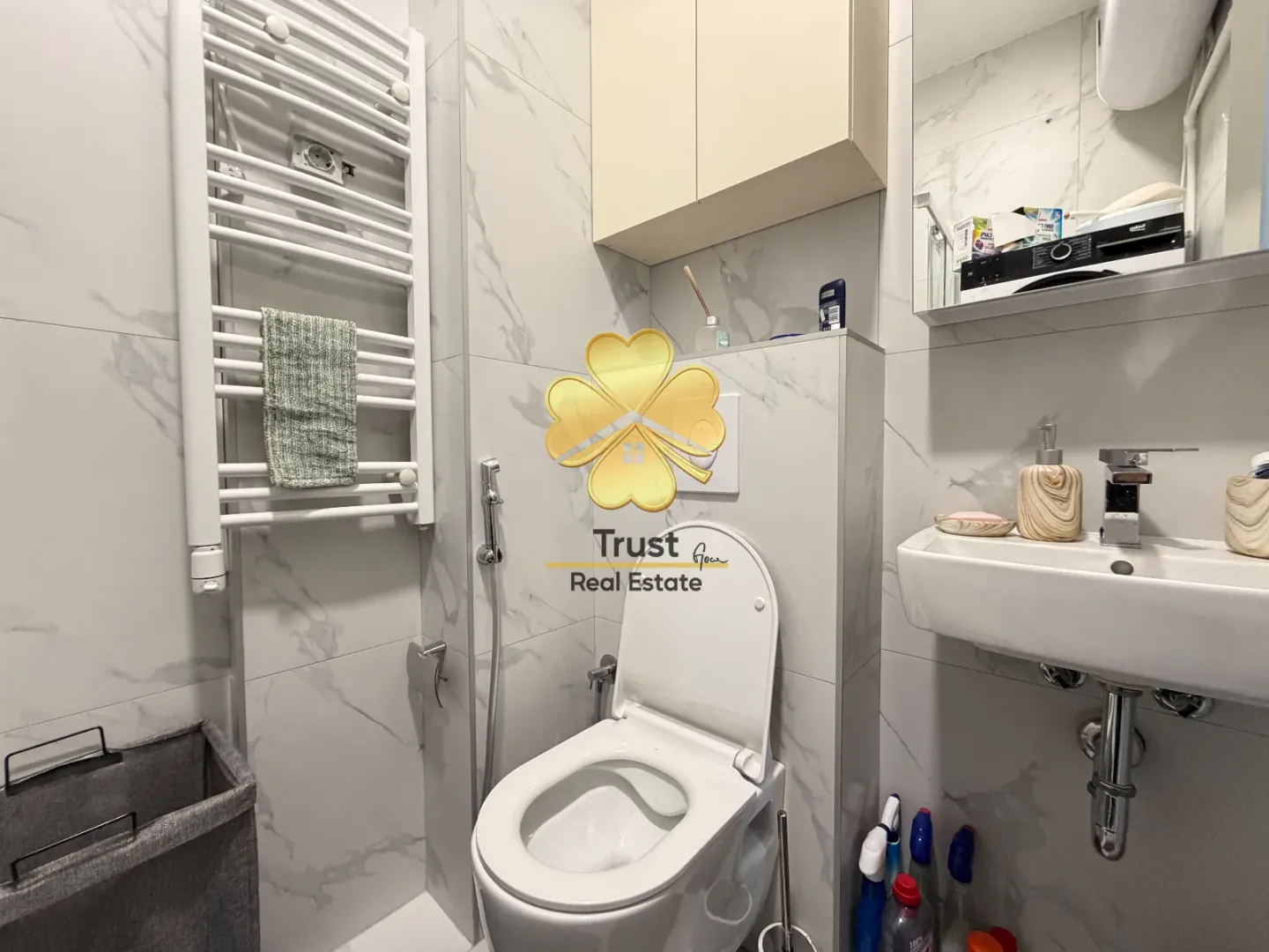 Modernly equipped bathroom with light tiles, toilet, and washbasin.