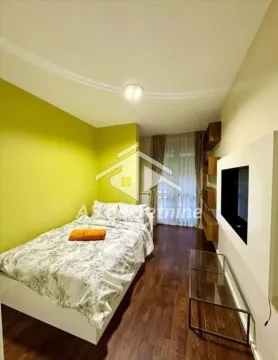 Manja spavaća soba sa krevetom, zelenim zidom i televizorom. - image 8