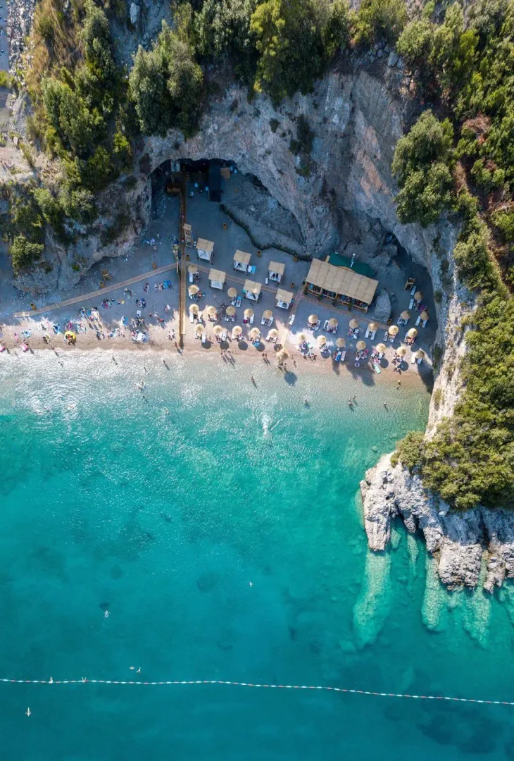 Pogled iz vazduha na pješčanu plažu i tirkizno more u uvali.