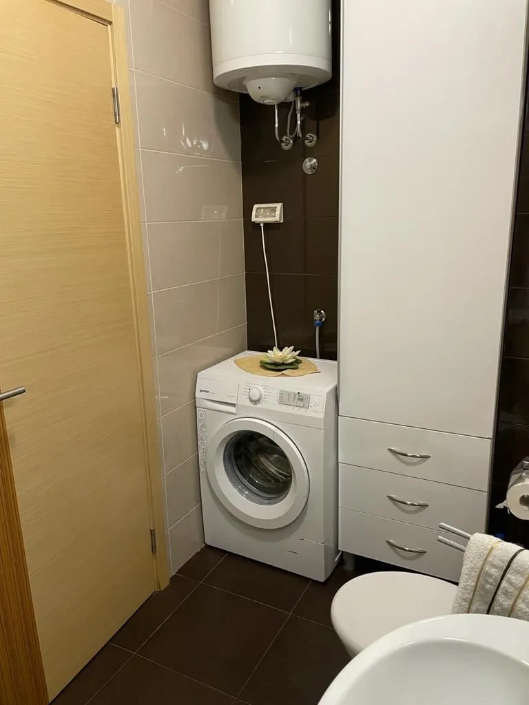 Part of a bathroom featuring a washing machine and a tall storage cabinet.