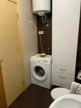 Part of a bathroom featuring a washing machine and a tall storage cabinet. - image 7