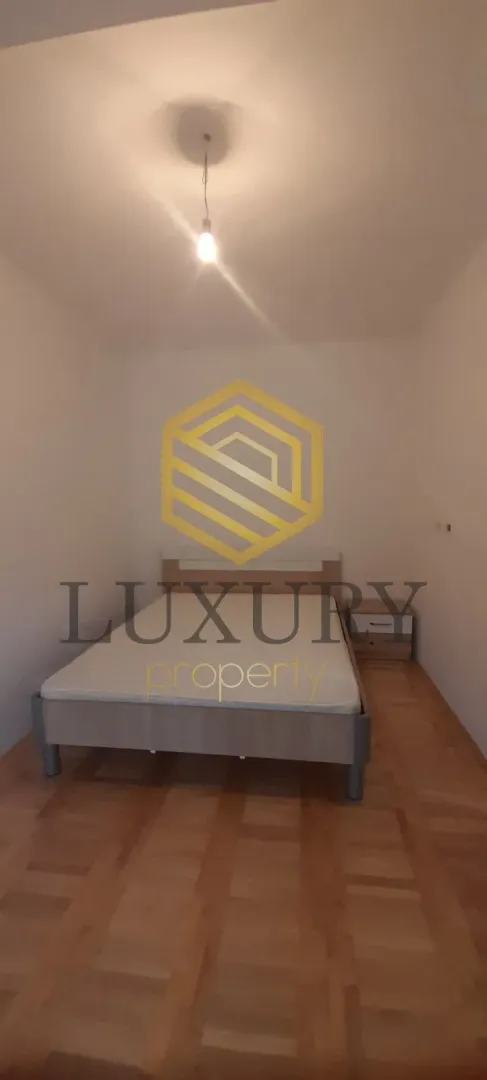 Empty bedroom with a double bed and parquet flooring.