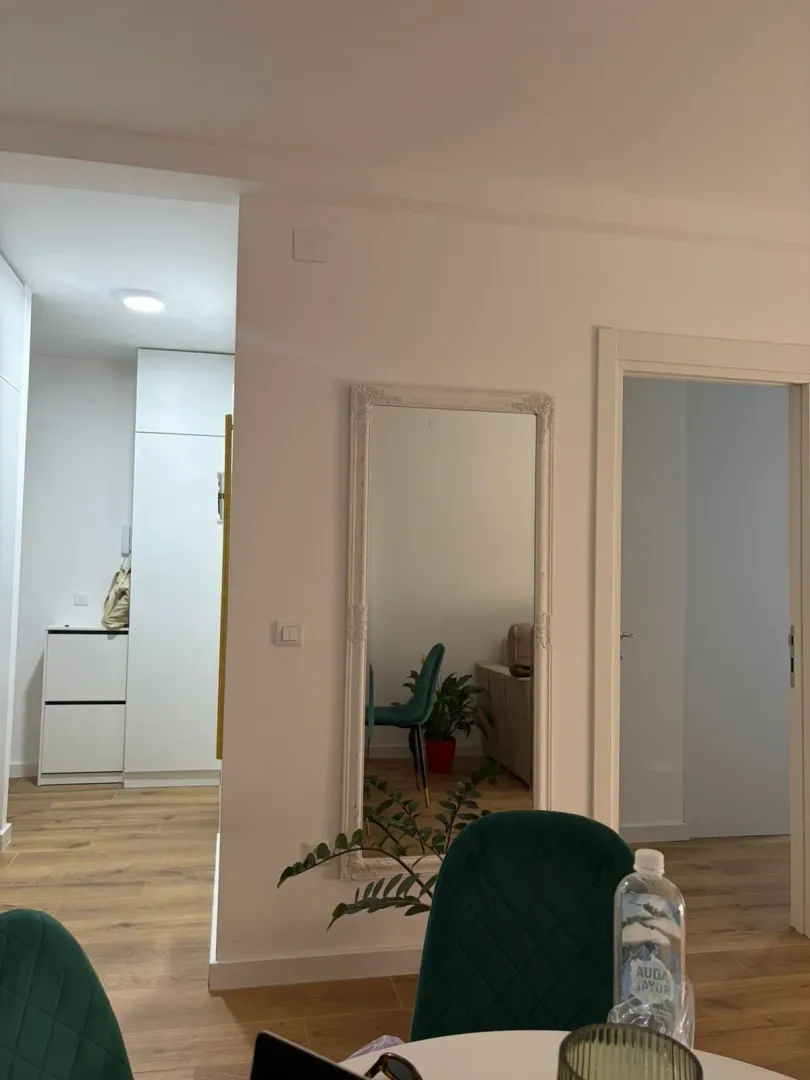 View of the living room interior with a dining table and a wall mirror.