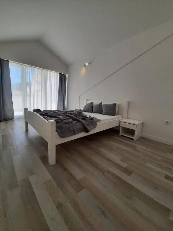 Prostrana spavaća soba sa bračnim krevetom i drvenim podom.