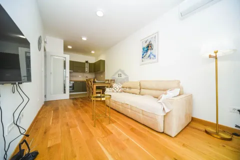 Living room with sofa, television and a view of the kitchen in the background. - image 3