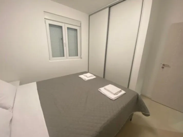 Svjetla spavaća soba sa bračnim krevetom, plakarom i prozorom.