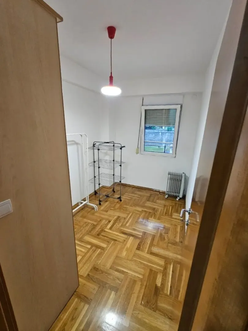 Prazna soba sa parketom i prozorom.