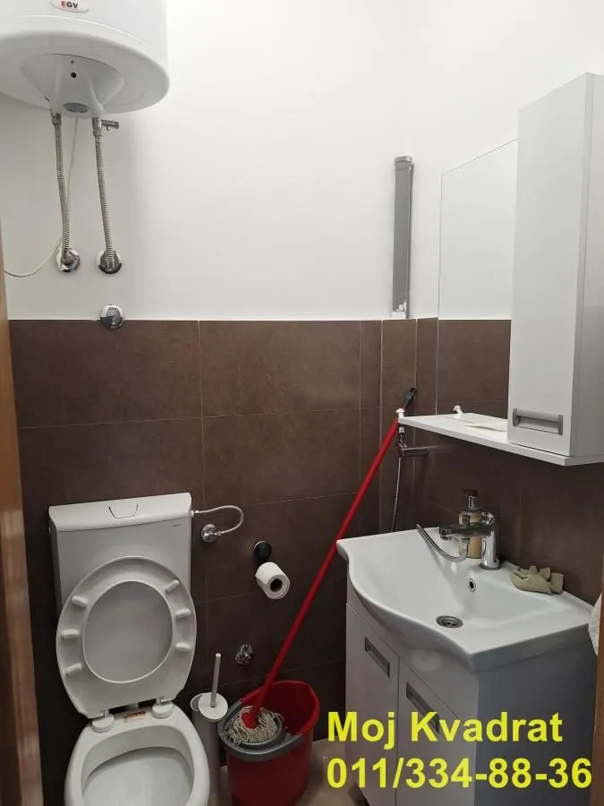 Smaller bathroom with a toilet, washbasin, and water heater.