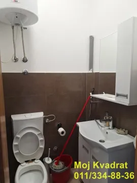 Smaller bathroom with a toilet, washbasin, and water heater. - image 8