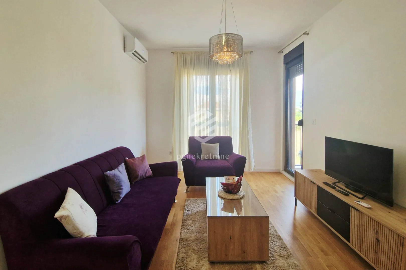 Living room with a purple sofa set, TV cabinet, and access to the terrace.