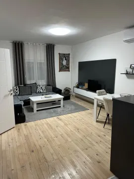 Spacious living room with a sofa set, dining table, and wooden flooring. - image 2