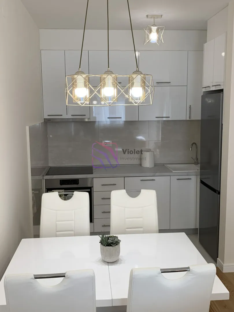Kitchen with white cabinetry and a dining table in the foreground.