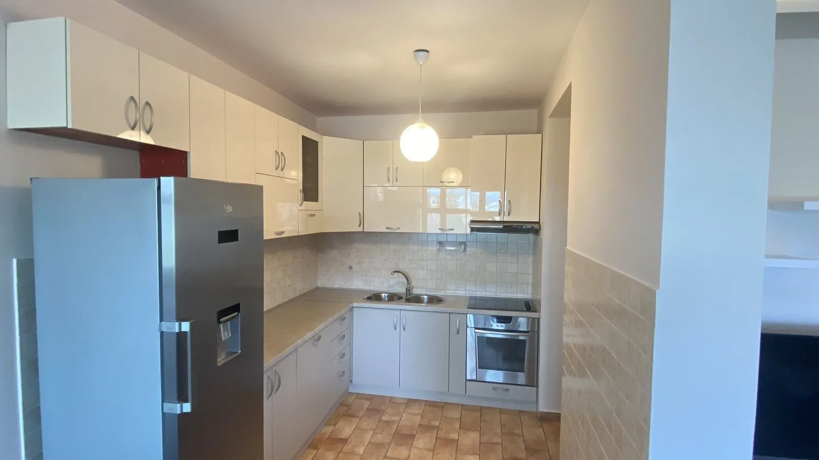 A bright kitchen with white cabinets and a refrigerator.