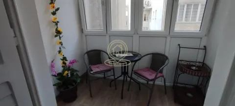 Zastakljeni balkon opremljen stolom, dve stolice i dekorativnim biljkama. - image 8