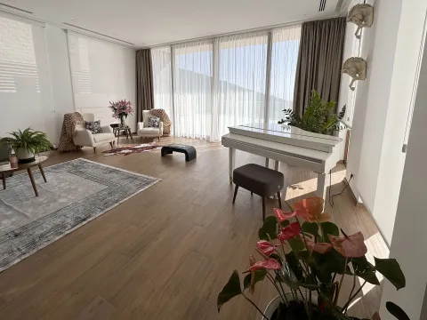 Spacious living room with a piano and large windows offering a view of the outside. - image 28