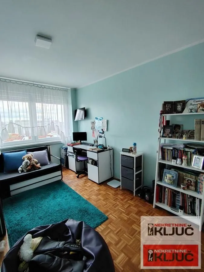 Dečja soba opremljena krevetom, radnim stolom i policama za knjige.