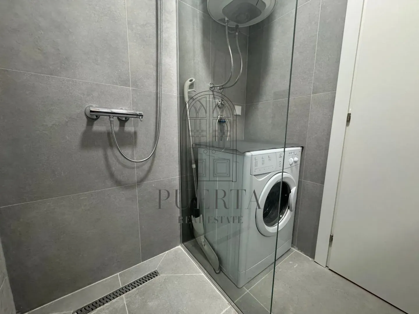 Modernly equipped bathroom with a shower cabin and washing machine.