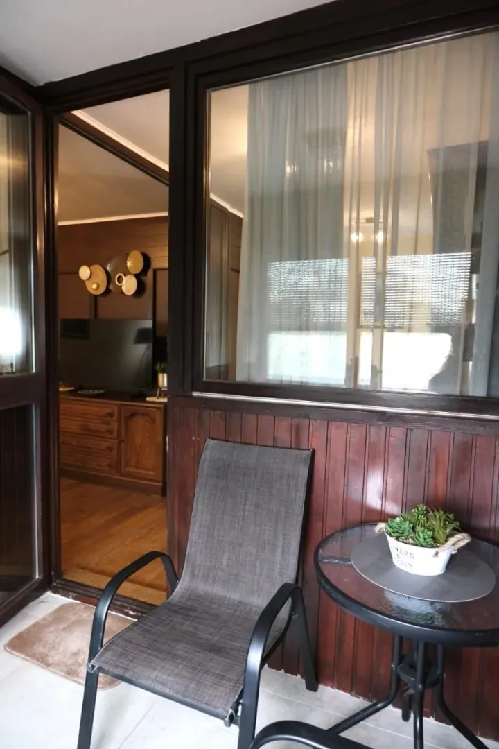 A terrace with a chair and table, looking into the apartment interior.