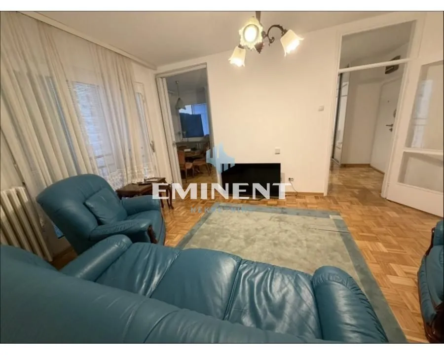 Living room with blue leather sofas, parquet flooring, and access to the terrace.