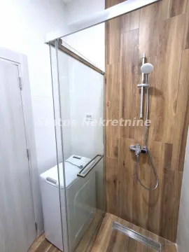 Bathroom with a shower cabin and a washing machine. - image 12