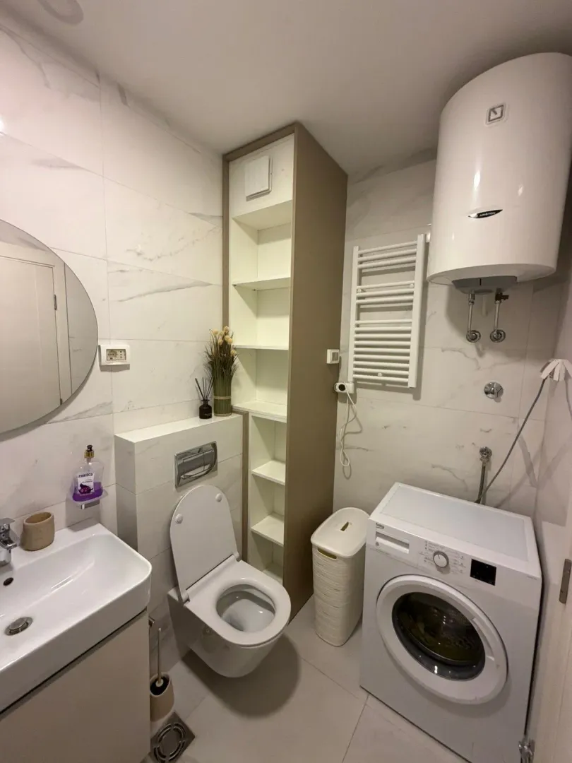 Modernly equipped bathroom with sanitary fixtures, water heater, and washing machine.