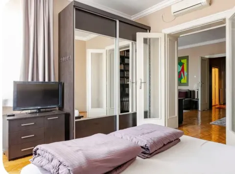 Furnished bedroom with a large wardrobe, bed, and television. - image 11