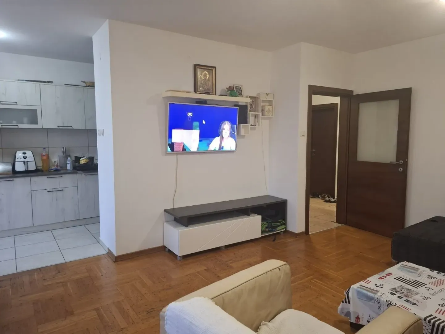 Dnevna soba sa televizorom i pogledom na kuhinju u pozadini.