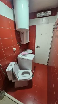 Manje kupatilo obloženo crvenim pločicama sa wc šoljom, mašinom za veš i bojlerom. - image 12