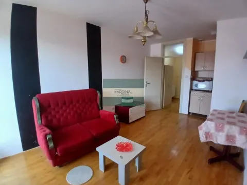 Living room with a red sofa, dining table, and kitchen in the background. - image 10