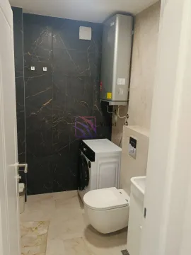 Compact bathroom with a toilet, washbasin, washing machine, and water heater. - image 9