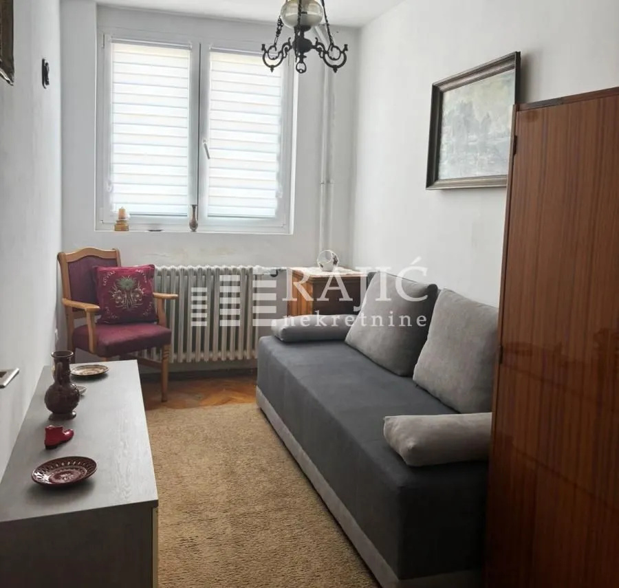 Small living room with a sofa, armchair and window.