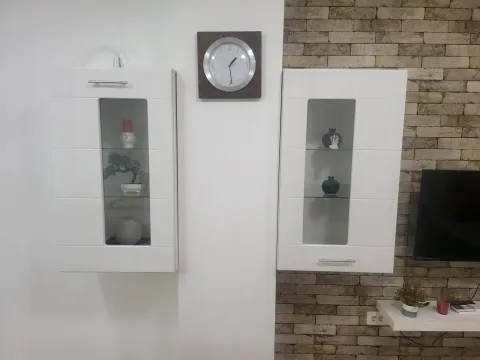 Wall cabinets and a clock in a living room with an accent wall. - image 6