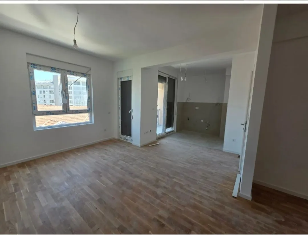Empty living room with wooden flooring and a window view.